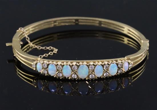 A 20th century pierced gold and graduated seven stone white opal set hinged bracelet,